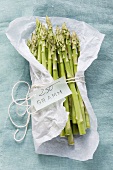 Green asparagus in parchment paper with a weight label