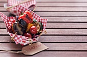 Barbecued vegetables skewers on a napkin in a cardboard container