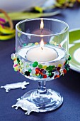 Floating candle in glass decorated with confetti & lucky pig charms