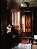 Colonial style, antique armoire with mirror and boots on wood flooring in the corner of a country bedroom