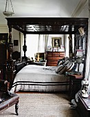 Double bed with dark wood canopy on colonial style, carved posts
