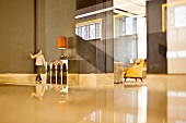 Grossräumiges minimalistisches Hotelfoyer mit glänzendem Boden und Frau im Hintergrund