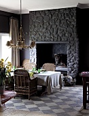 Dining table in front of dark stone chimney breast on vintage-style chequered floor