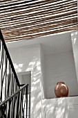Sonneneinfall durch Bambussdach ins Treppenhaus und Blick auf Amphore in Wandnische