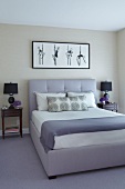 Lilac double bed with upholstered headboard below framed picture of dancers and flanked by bedside tables