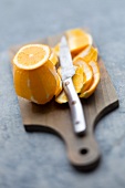 A peeled orange on a chopping board with a knife