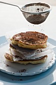 Chocolate pancakes being dusted with cocoa powder