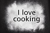 'I love cooking' etched in icing sugar on a black background