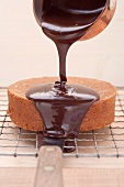 Sachertorte (rich chocolate cake from Austria) being coated with chocolate glaze