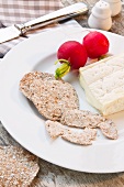 A snack of Camembert, rye crackers and radishes