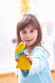 A girl holding a biscuits in the shape of an Easter bunny with yellow icing