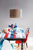 Antiker Tisch, mit farbig gestrichenen, alten Zaunlatten in neuem maritimem Streifenlook, ergänzt durch Lampenschirm mit Schriftprint und Vintage Stühlesammlung