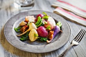 Baby Root Vegetable Salad on a Metal Plate; On a Wooden Table
