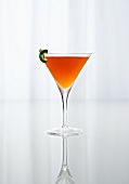 An Orange Cocktail in a Stem Glass on a Reflective Surface