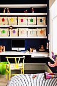 Fabric storage bins with colorful labels in shelves above a writing desk in a children's room