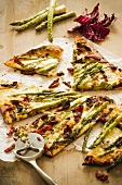 Sliced Asparagus and Sun Dried Tomato Pizza with a Pizza Cutter