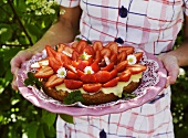 A woman holding a strawberry cake with vanilla cream