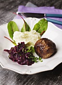 A meatball with mashed potato and red cabbage