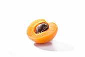 Half an apricot with the stone in against a white background