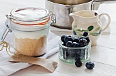 A preserving jar with dry ingredients for making cheesecake, blueberries to one side