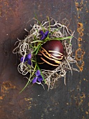 An egg painted in shades of brown for Easter, in a nest (view from above)