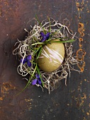 A green decorated egg for Easter in a nest