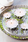 Candle arrangement with cake moulds, decorative pebbles and glory-of-the-snow flowers