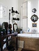 Collection of busts, figurines and mirrors on console table and wall-mounted shelves over bathtub