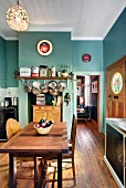 Turquoise, traditional-style kitchen with pots and pans hanging over wooden cabinet