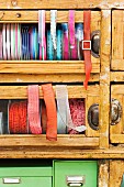 Spools of various ribbons in glass-fronted drawers of vintage cabinet