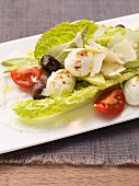 Caesar salad with mozzarella, olives and tomatoes