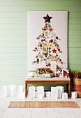 Weihnachtsbaumanhänger an weißem Paneel in Weihnachtsbaum-Form arrangiert, davor Geschenke und Papiertüten als Windlichter