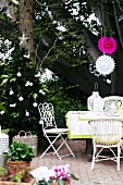 Festively decorated terrace with set terrace table and white chairs; potted flowering plants in foreground