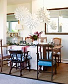 White paper Advent stars above festively decorated table and various chairs