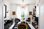 Moderne, schwarze Ledergarnitur und mit Goldschrift verzierte Renaissance Stühle in elegantem Wohnzimmer