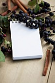 A notepad surrounded by fresh aronia berries