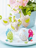 Easter decoration - fabric hens, egg-shaped candles and chocolate eggs on white platter