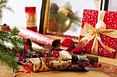 Rolls of wrapping paper and ribbons next to wrapped Christmas present with bow