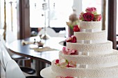An elegant wedding cake decorated with white ribbons and pink roses