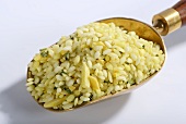 Vialone Nano risotto rice with almonds, lemon oil, turmeric and chives on a brass scoop