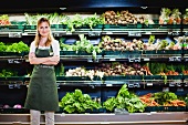 Verkäuferin steht in der Gemüseabteilung im Supermarkt