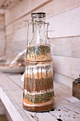 Assorted spices and herbs layered in a swing-top bottle
