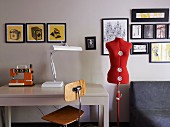 Interior with gallery of pictures, tailor's dummy & table with sewing machine and table lamp