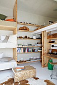 Space-saving bunk beds next to DIY wooden shelving on wall with cowhide rug in foreground