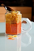 Dried pasta and red lentils in a storage jar with a scoop
