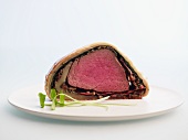 Beef Wellington on a plate against a white background
