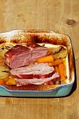 Roast ham with vegetables in the roasting tin