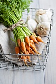 A bunch of baby carrots and garlic in a basket