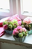 Small flower arrangements with pink roses in china flan dishes from the fifties