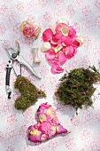 Materials for crafting decorative heart from moss, yarn and rose petals of various colours